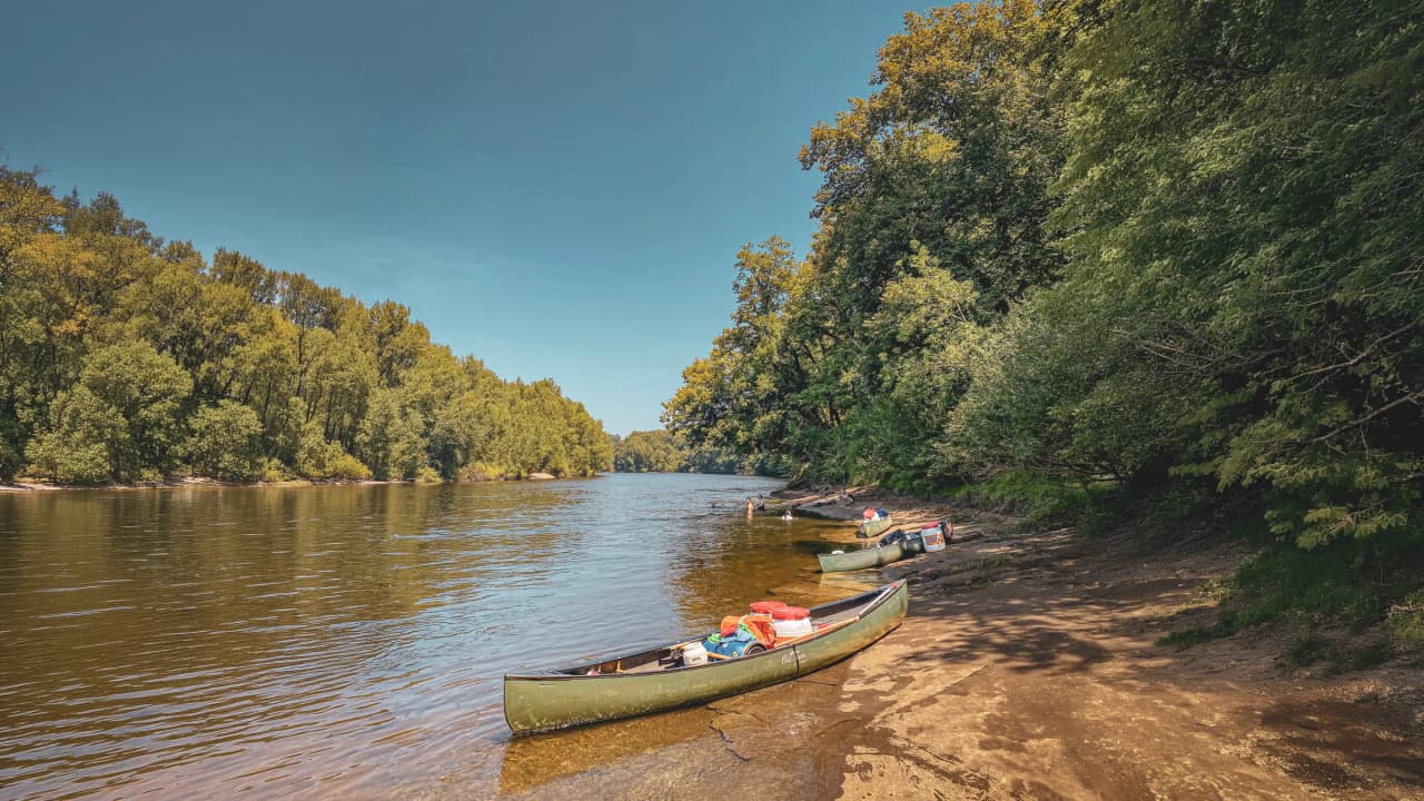 Canoës amarrés sur la rive de la Dordogne, entourés de verdure, invitent à l'évasion.
