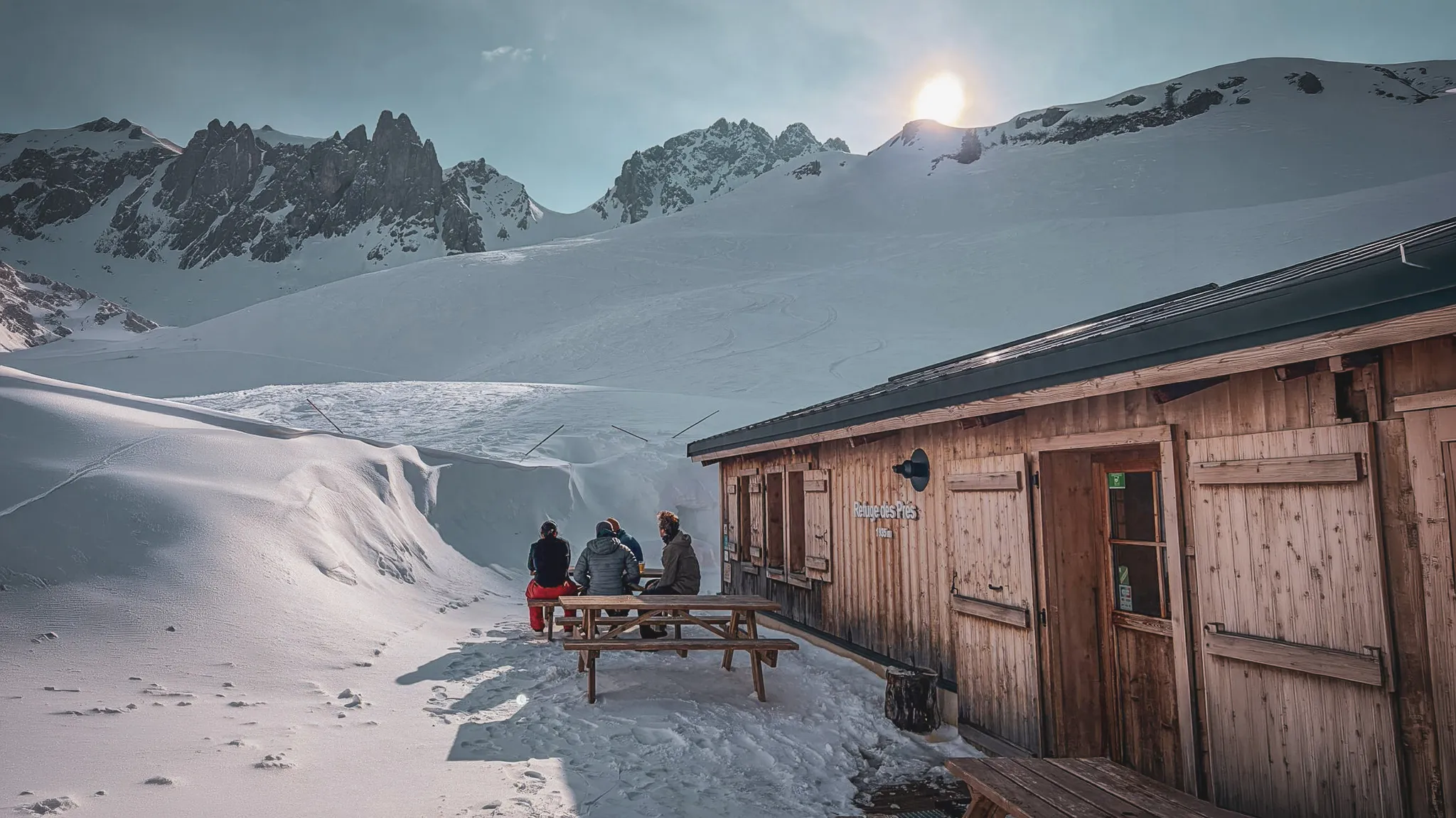 A welcoming wooden hut, with skiers admiring the snow-capped peaks of Mont Blanc.