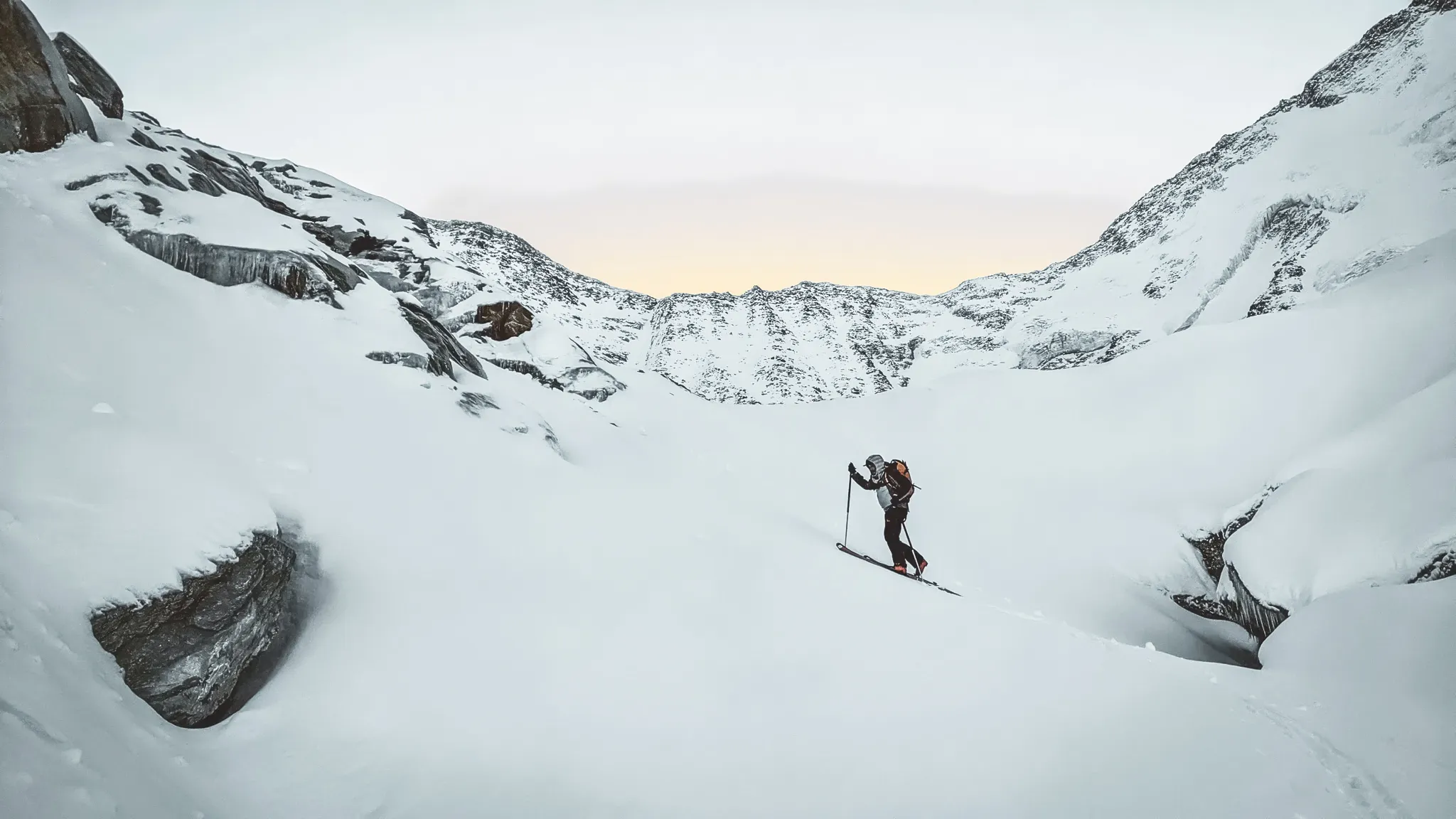 A ski tourer crosses a majestic snow-covered landscape, surrounded by impressive mountains.