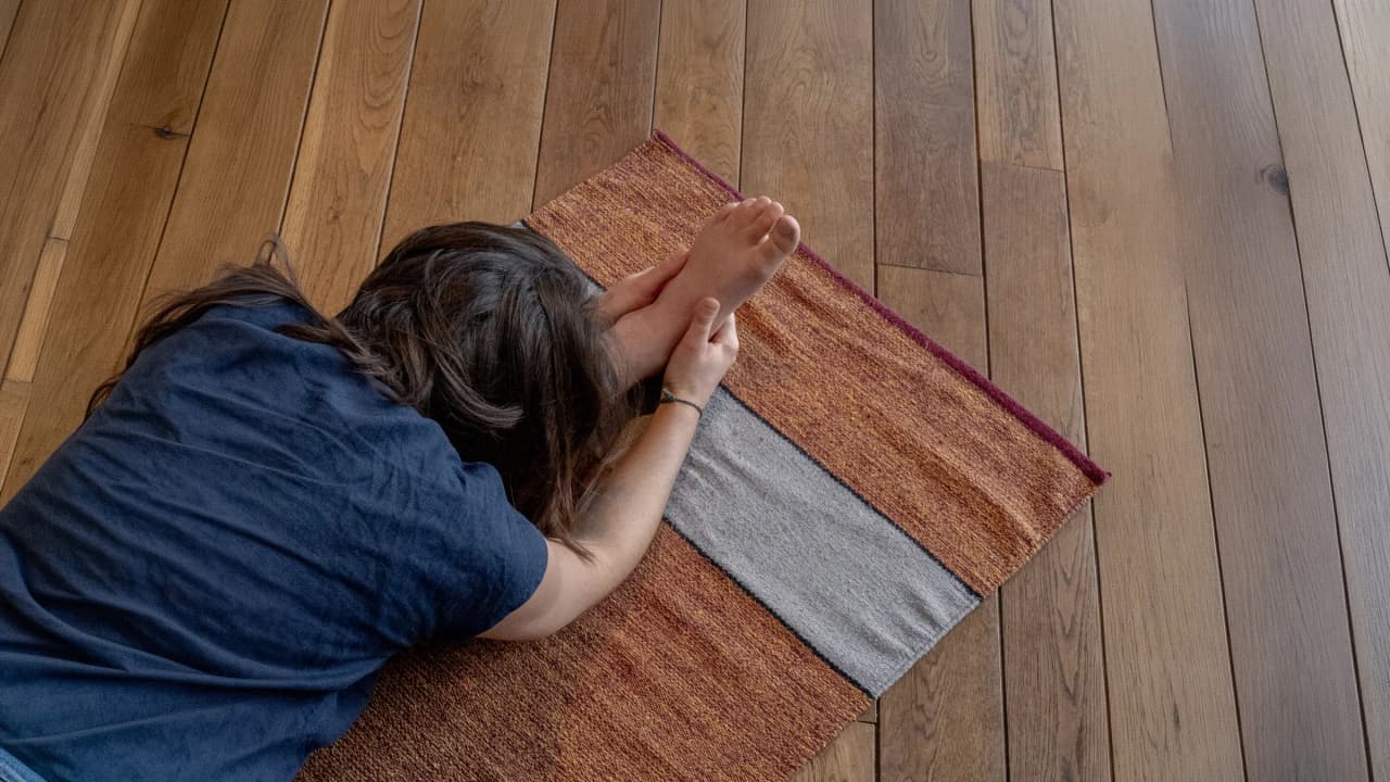 A person practising yoga on a colourful mat in a soothing, natural indoor setting.