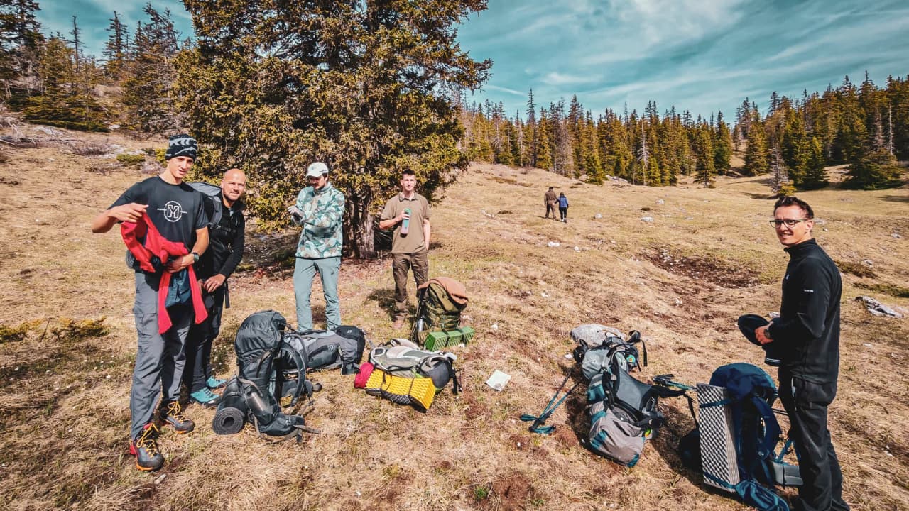 Un groupe d'amis se prépare pour une aventure en pleine nature, entre montagnes et forêts verdoyantes.