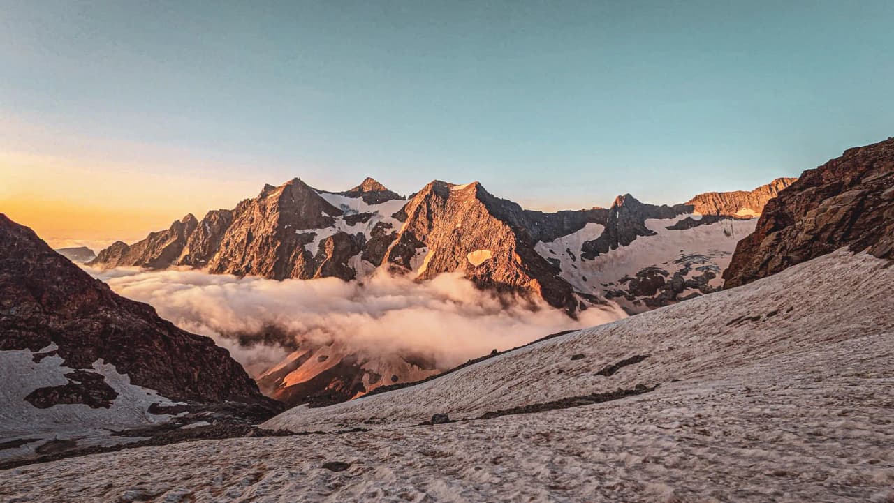 Majestueuses montagnes des Écrins baignées de lumière au lever du soleil, un spectacle enchanteur.
