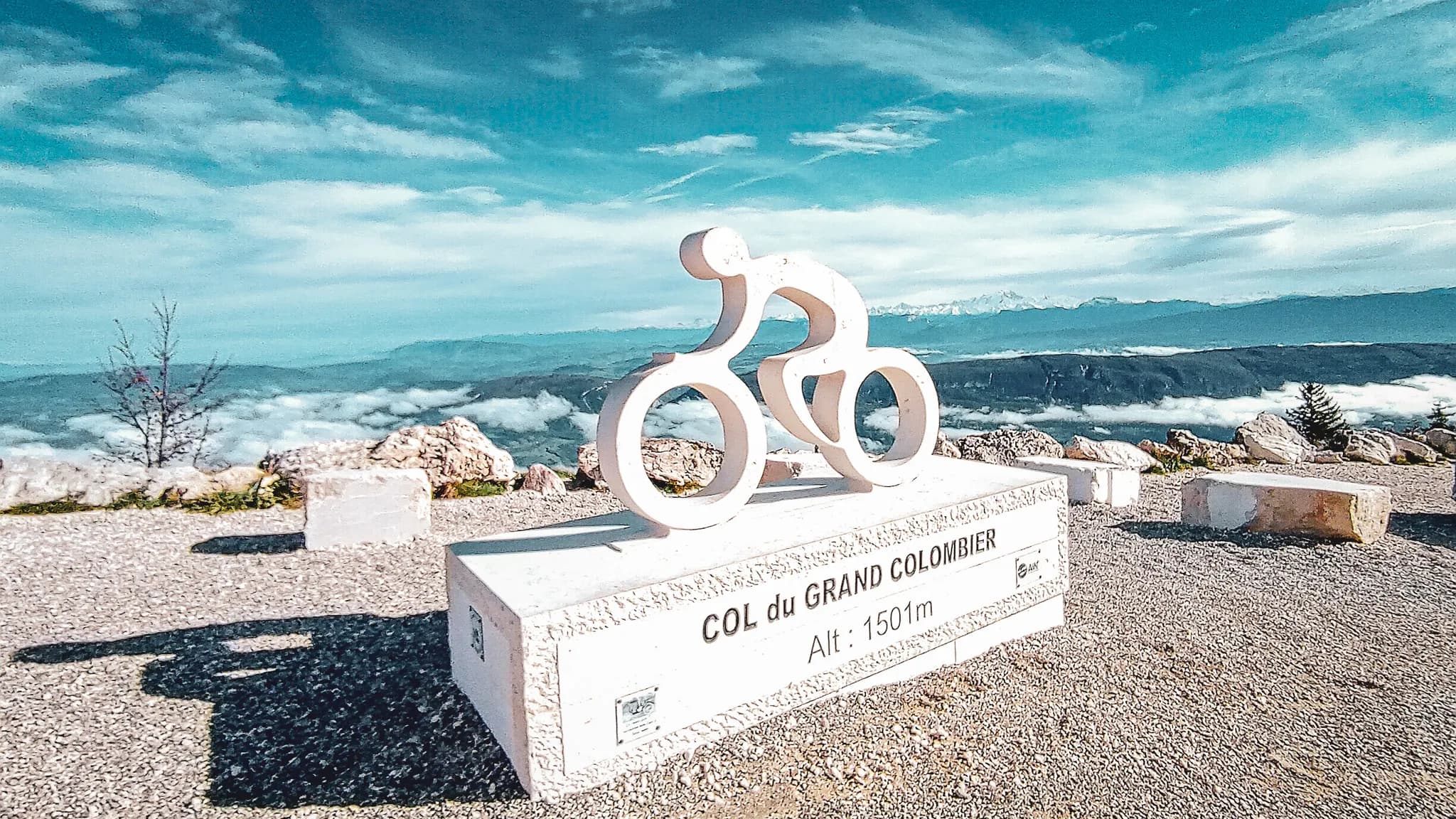 Gestileerd bord in de vorm van een fietser op de Col du Grand Colombier, met een panoramisch uitzicht op het Jura-massief.