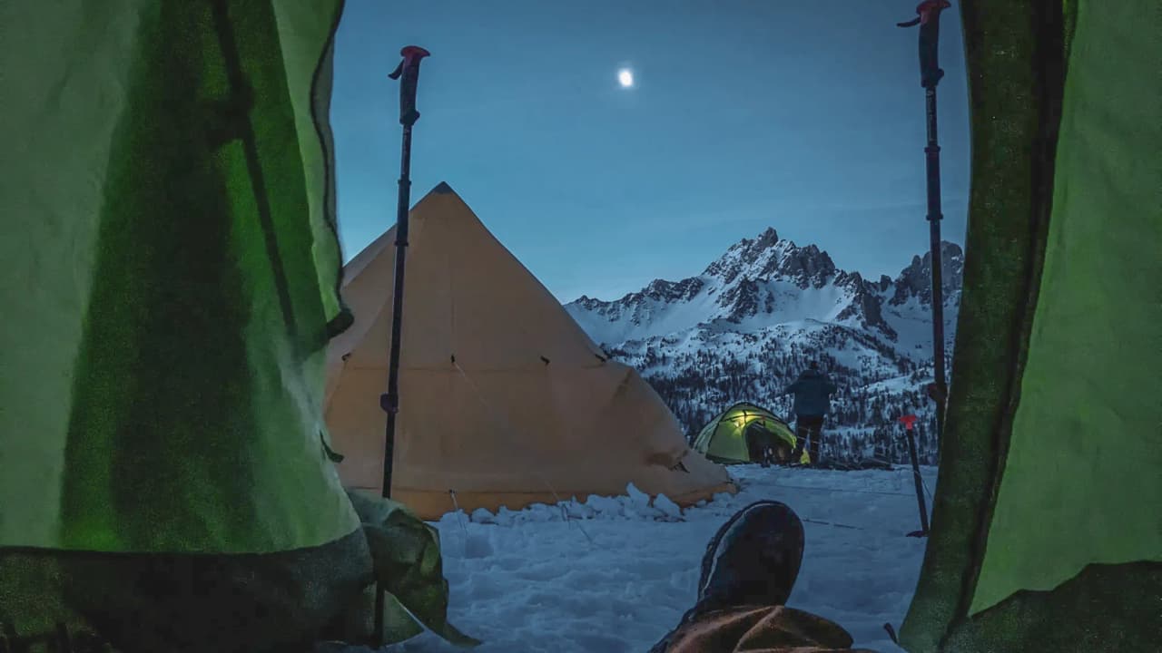 A view from inside a tent, with snow-capped mountains and a starry sky, inviting you to set off on an adventure.