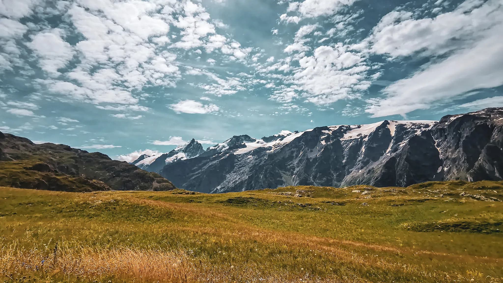 Panorama majestueux du plateau d'Emparis, montagnes et nuages dans un ciel lumineux.