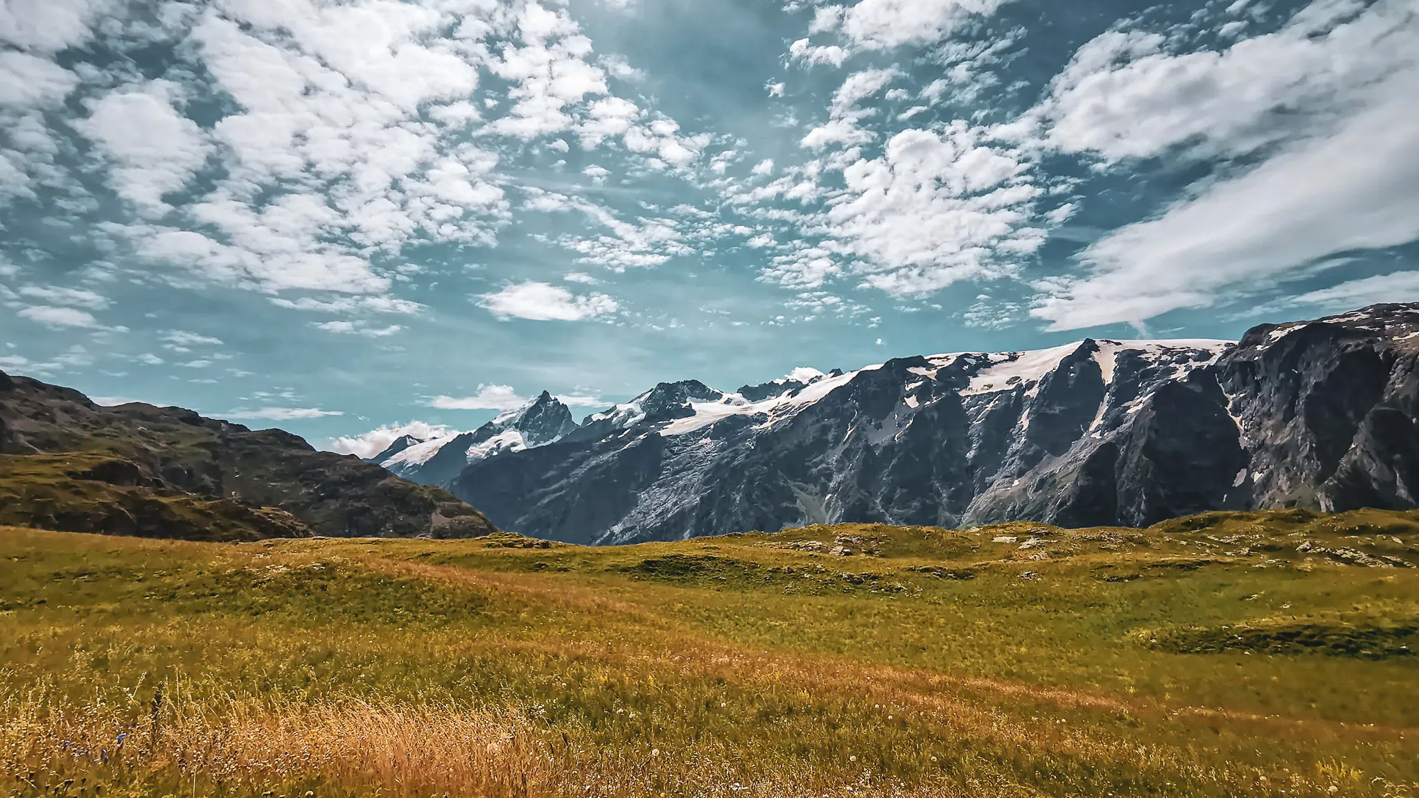 Panorama majestueux du plateau d'Emparis, montagnes et nuages dans un ciel lumineux.