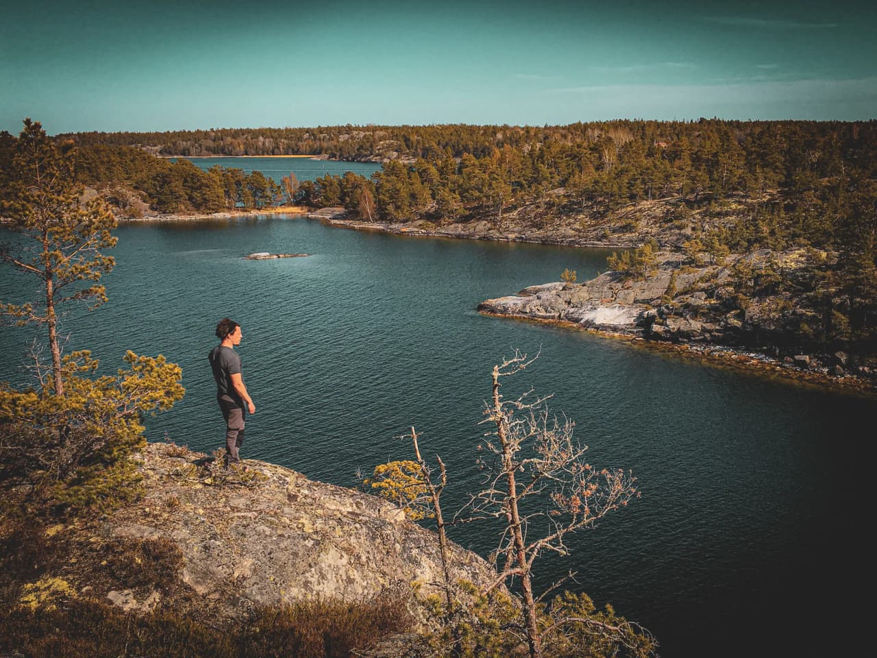 An adventurer contemplating the wild landscape of the Stockholm archipelago, surrounded by nature.