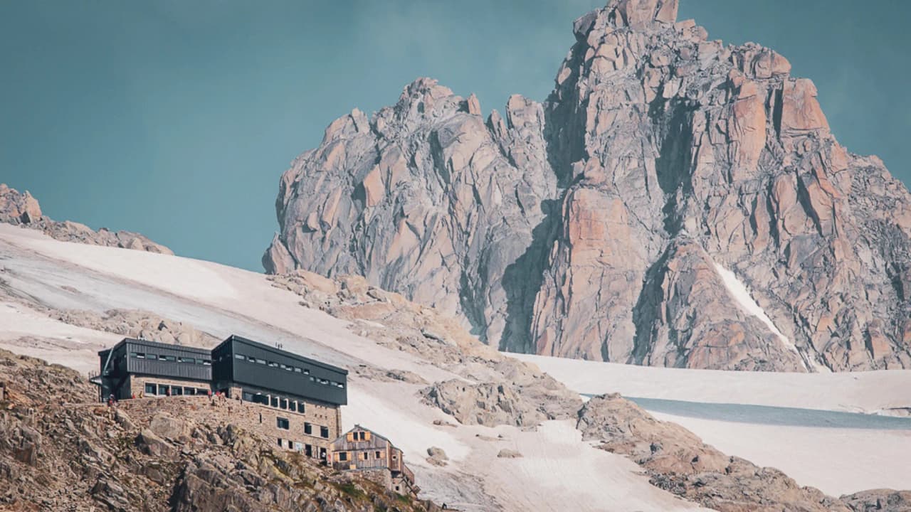 Een modern Berghut genesteld in een spectaculair Alpenlandschap, met majestueuze bergtoppen op de achtergrond.