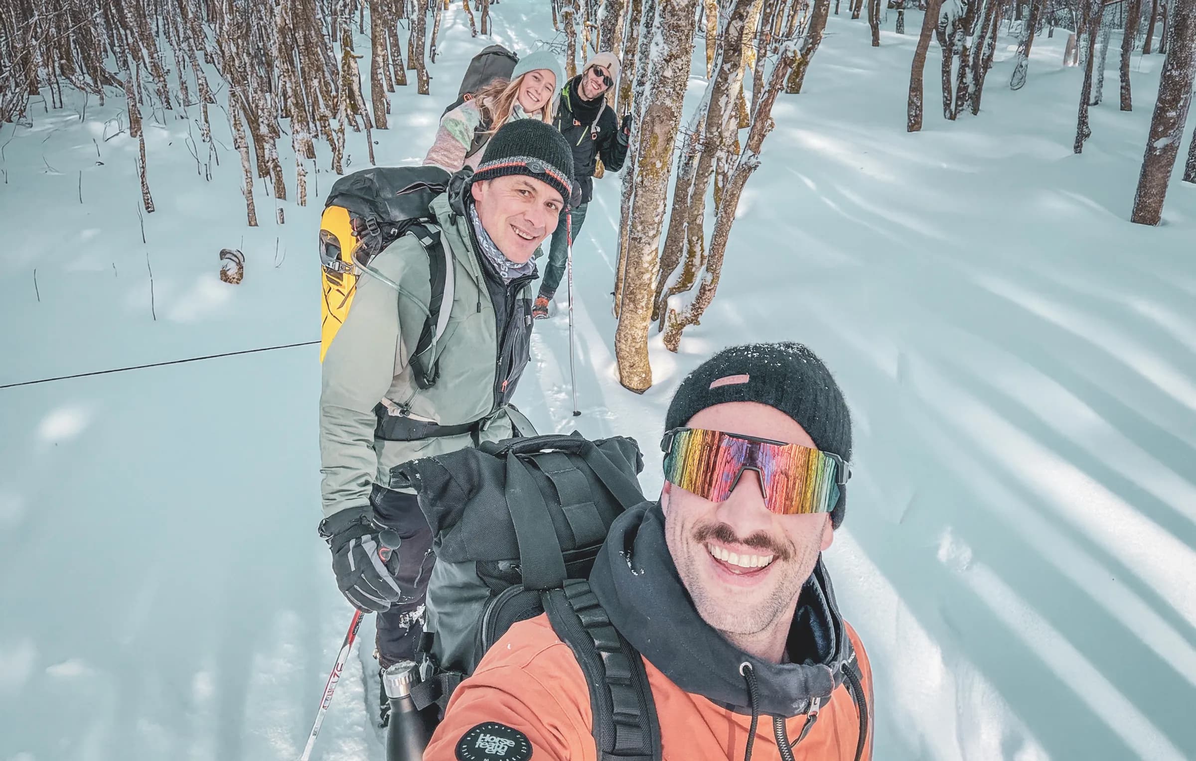 A group of smiling friends on snowshoes in a snowy forest in the Vosges. A winter adventure!
