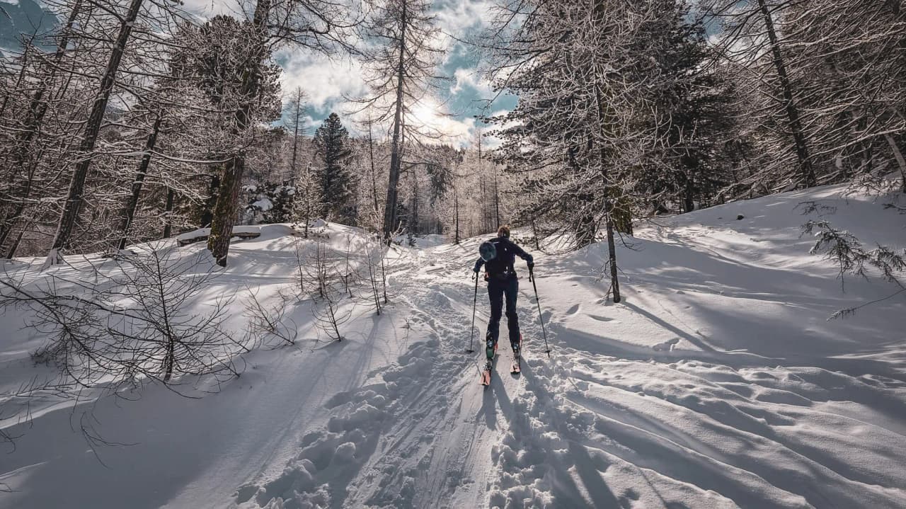 Skieur en pleine nature, traversant un paysage enneigé et ensoleillé des crêtes du Queyras.
