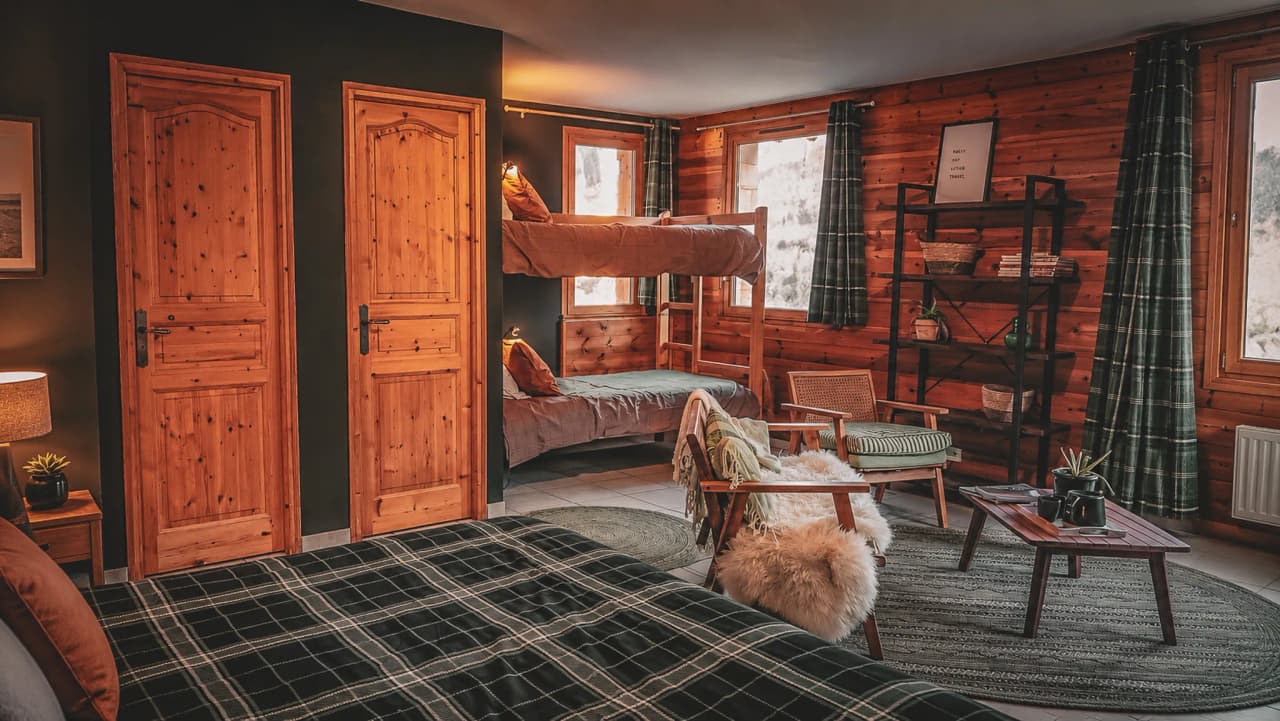 Chambre chaleureuse en bois, lits superposés et coin salon, parfaite pour une escapade en montagne.