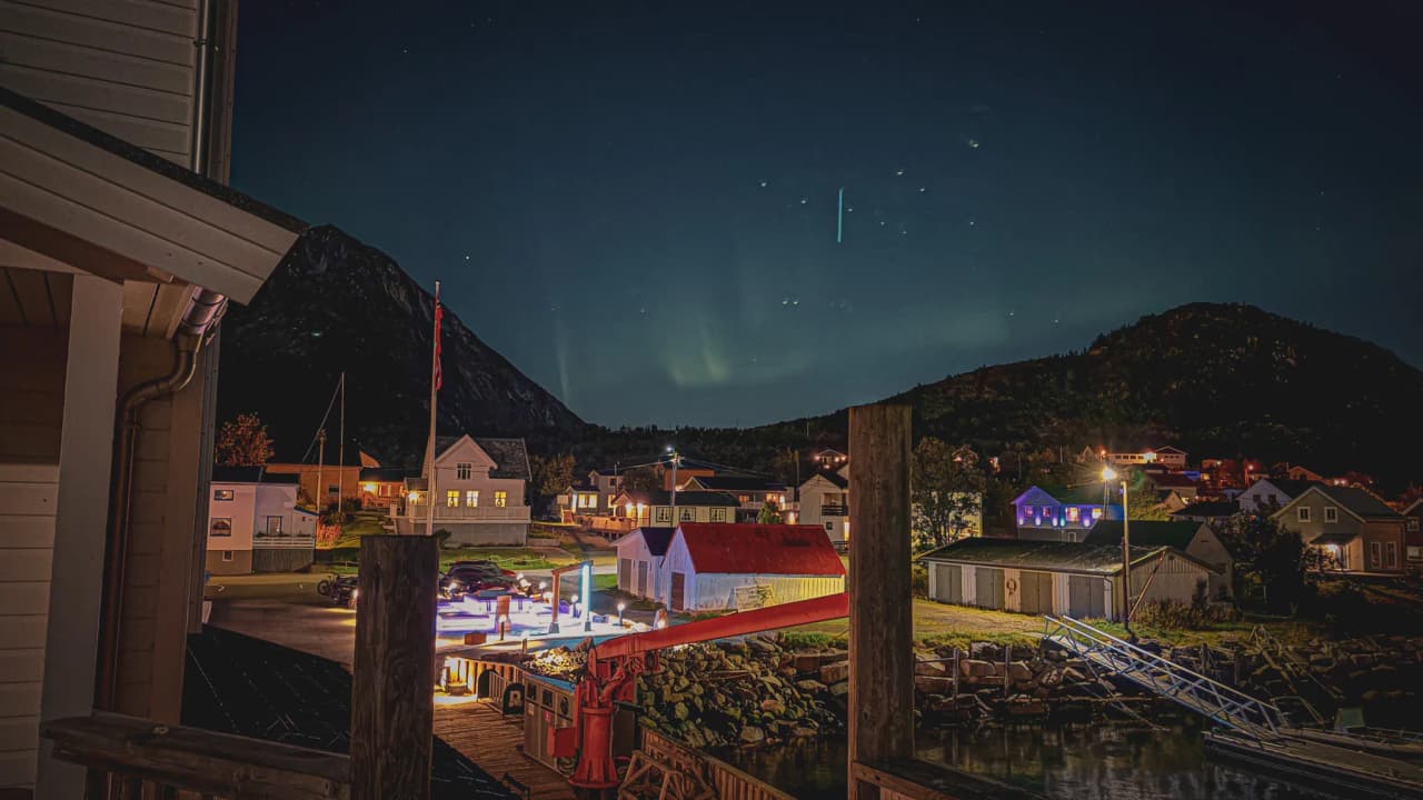 Een schilderachtig nachtzicht van een haven op het eiland Senja, verlicht door het noorderlicht.