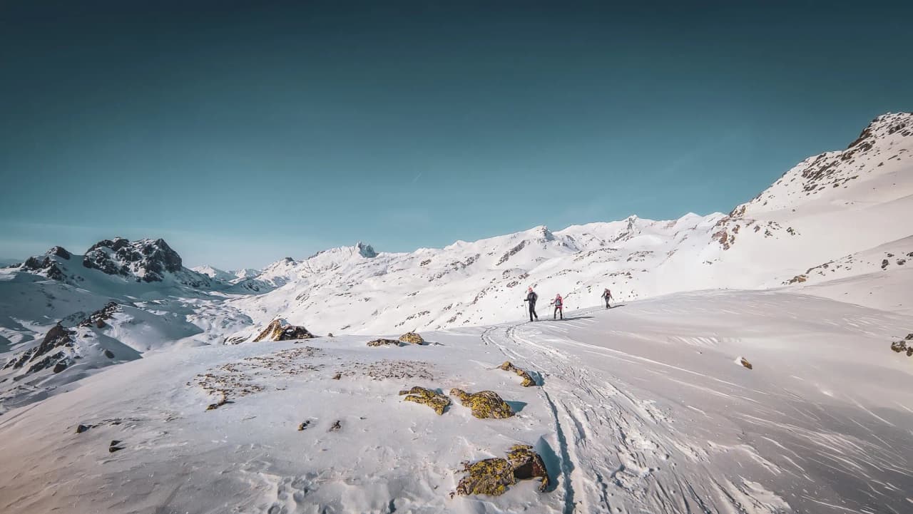 Snowshoe hikers on a snow-covered trail, with majestic views of the surrounding mountains.