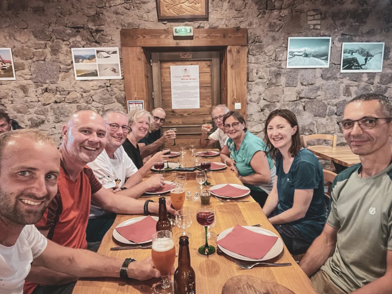 A cheerful group shares a mountain meal in a cosy Mountain hut in the Vosges.
