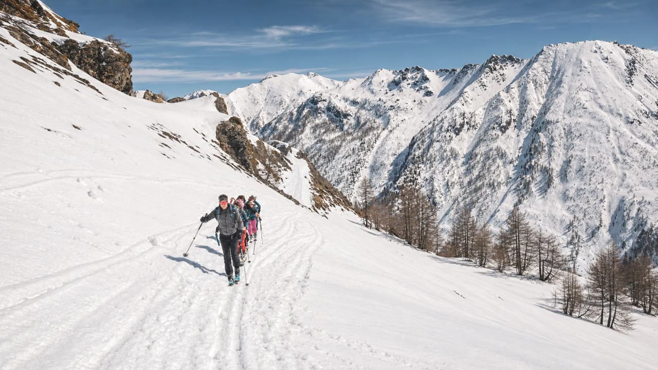 Groupe de randonneurs skiant sur une neige immaculée avec les sommets majestueux en arrière-plan.