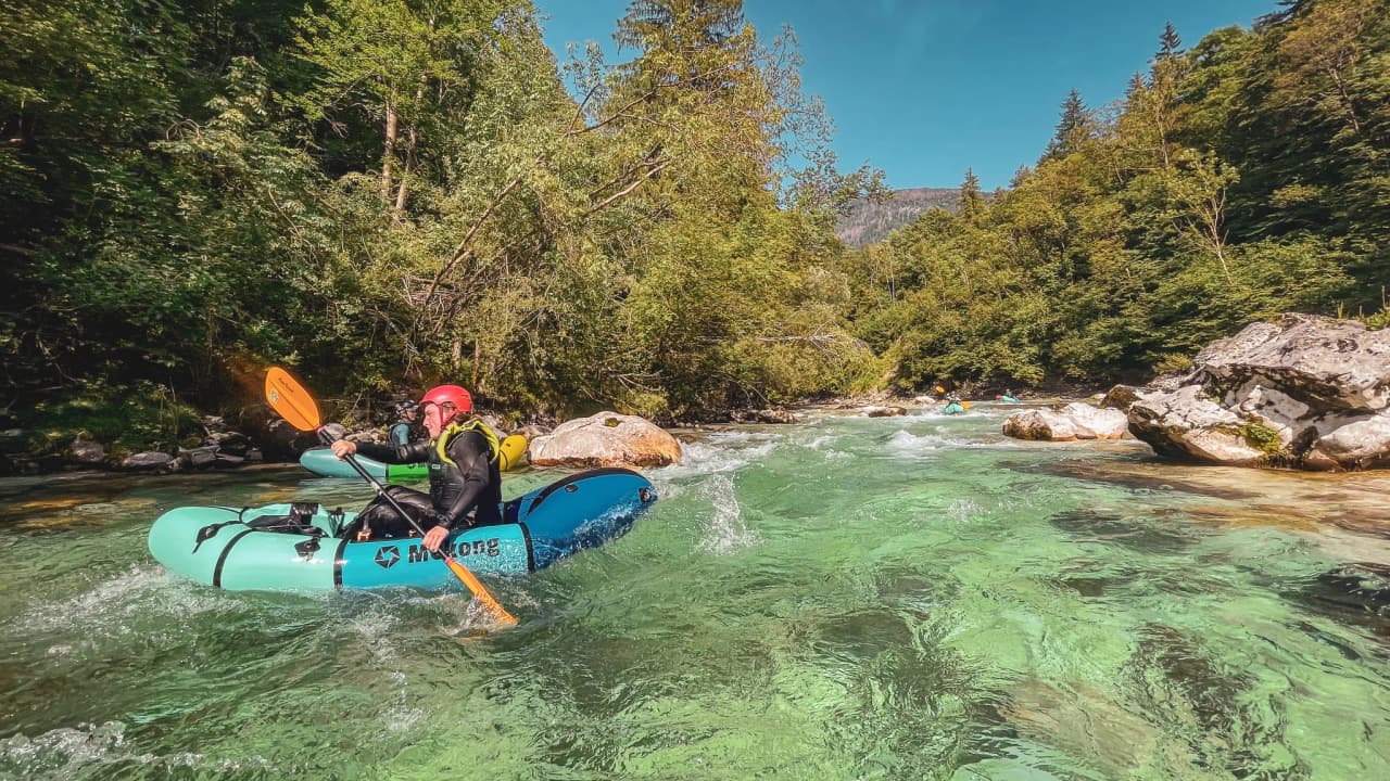 Paddle in hand, adventuring on a turquoise river, surrounded by alpine greenery in Slovenia.