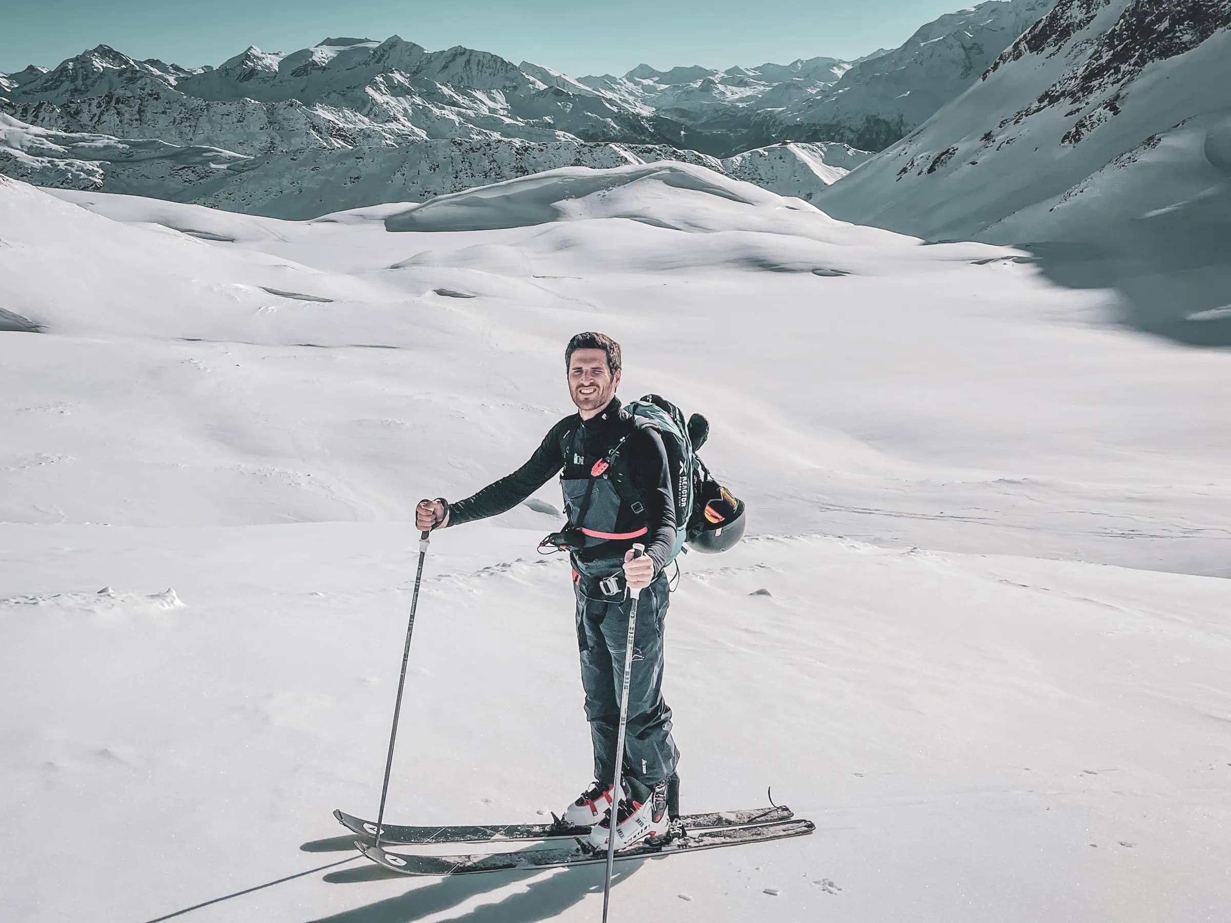 Smiling skier in the middle of a breathtaking glacial landscape, majestic mountains in the background.