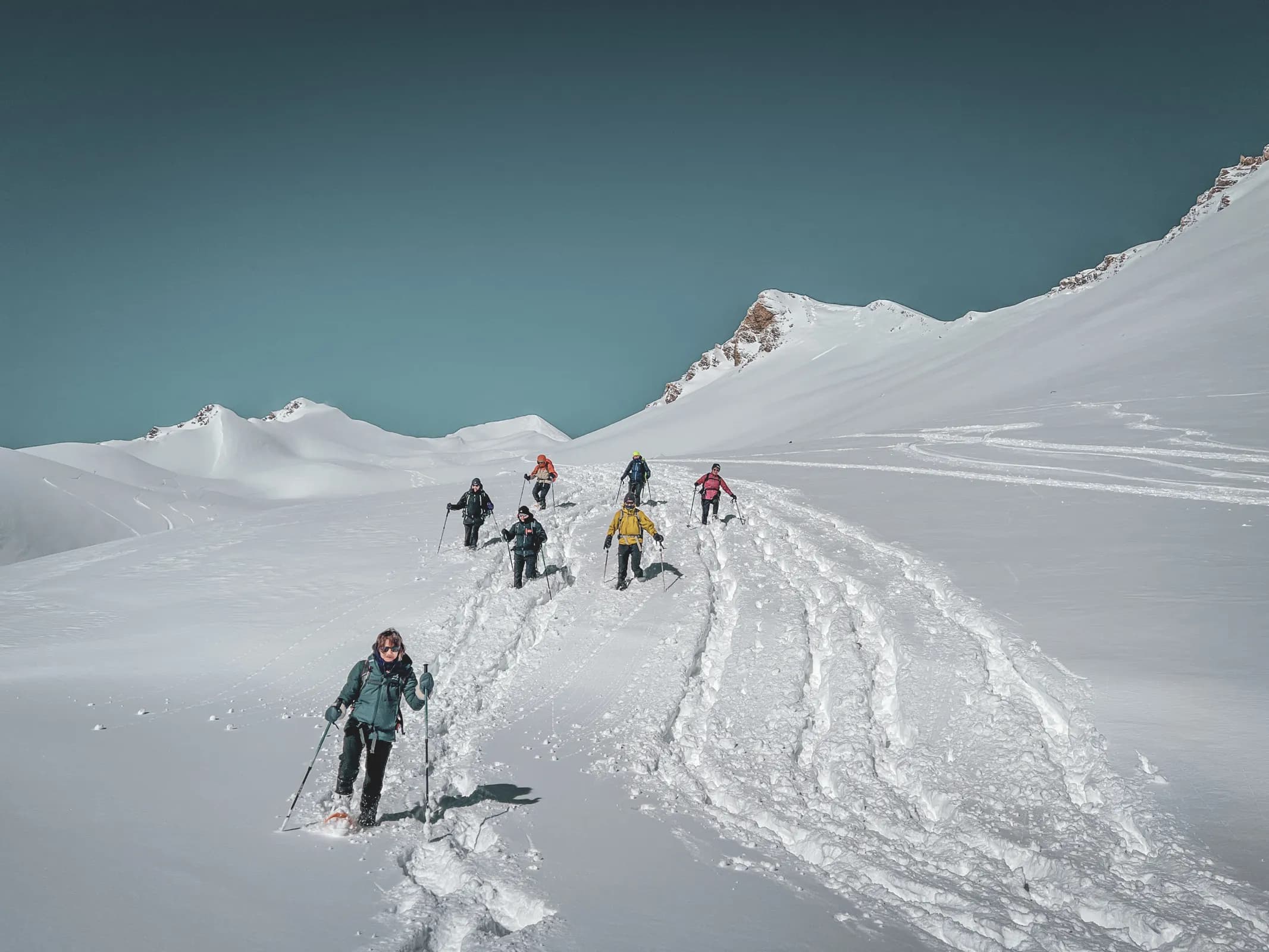 Groupe de randonneurs en raquettes, cheminant sur un plateau enneigé face aux majestueux glaciers.