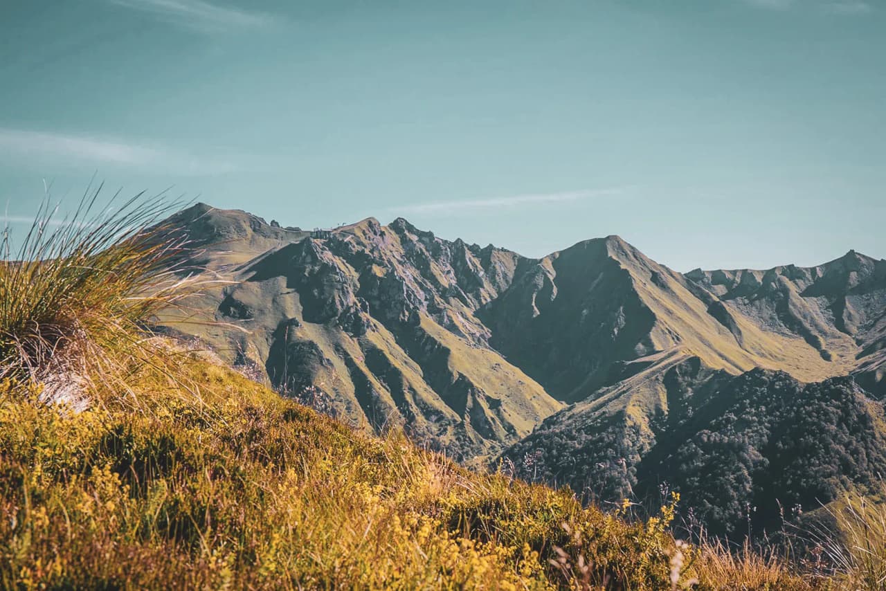 Het betoverende landschap van het Centraal Massief, met groene vulkaanruggen onder een helderblauwe hemel.