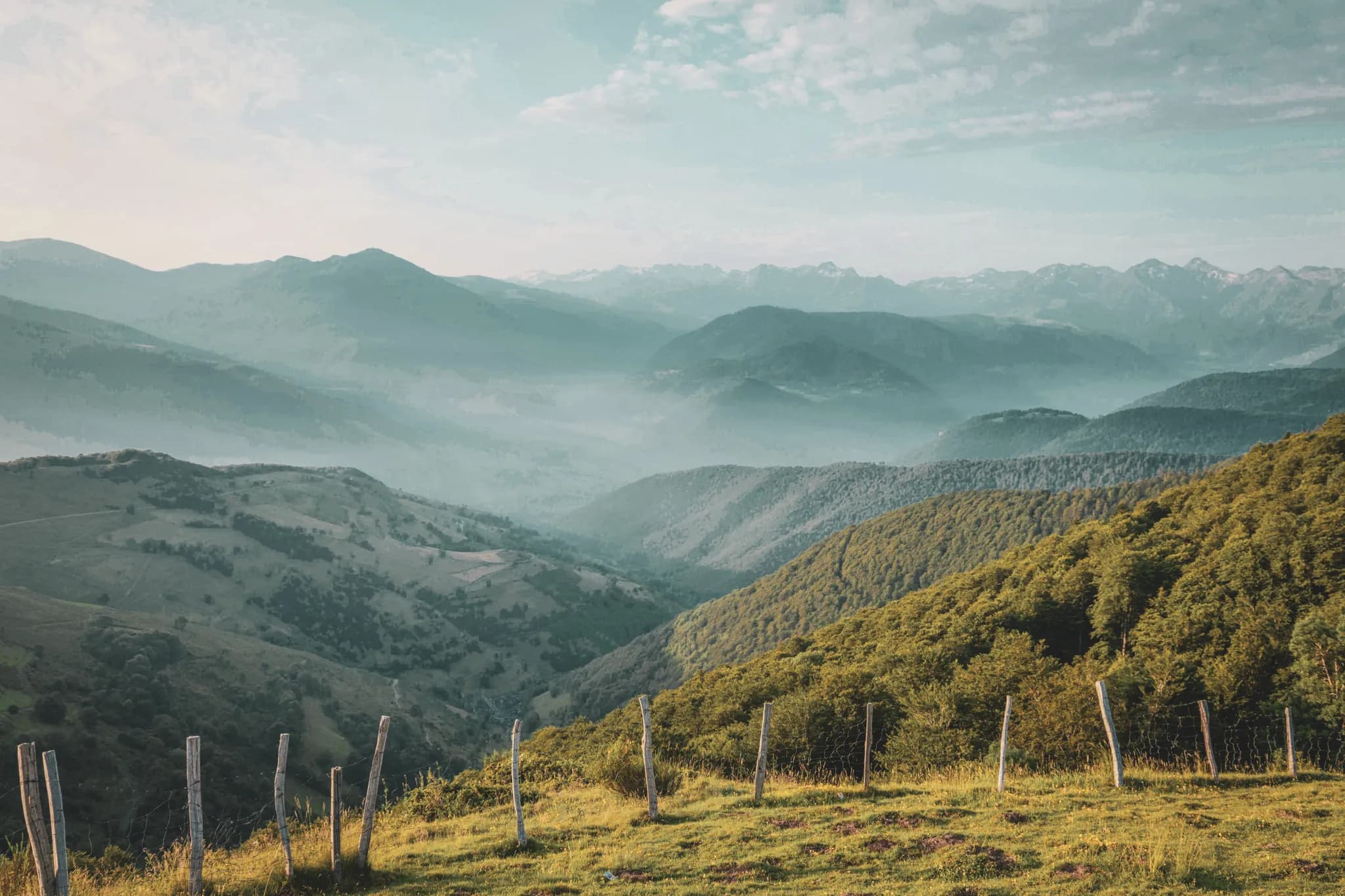 Een uitgestrekt panorama van de groene bergen van de Pyreneeën, badend in zacht ochtendlicht.