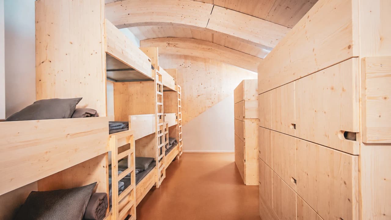 The modern wooden interior of a mountain hut, with bunk beds and a cosy atmosphere.