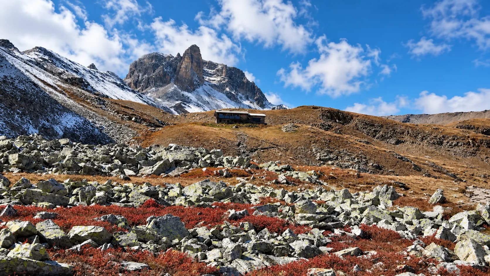 A spectacular mountain landscape with a mountain hut nestled amongst rocks and high-altitude lakes.