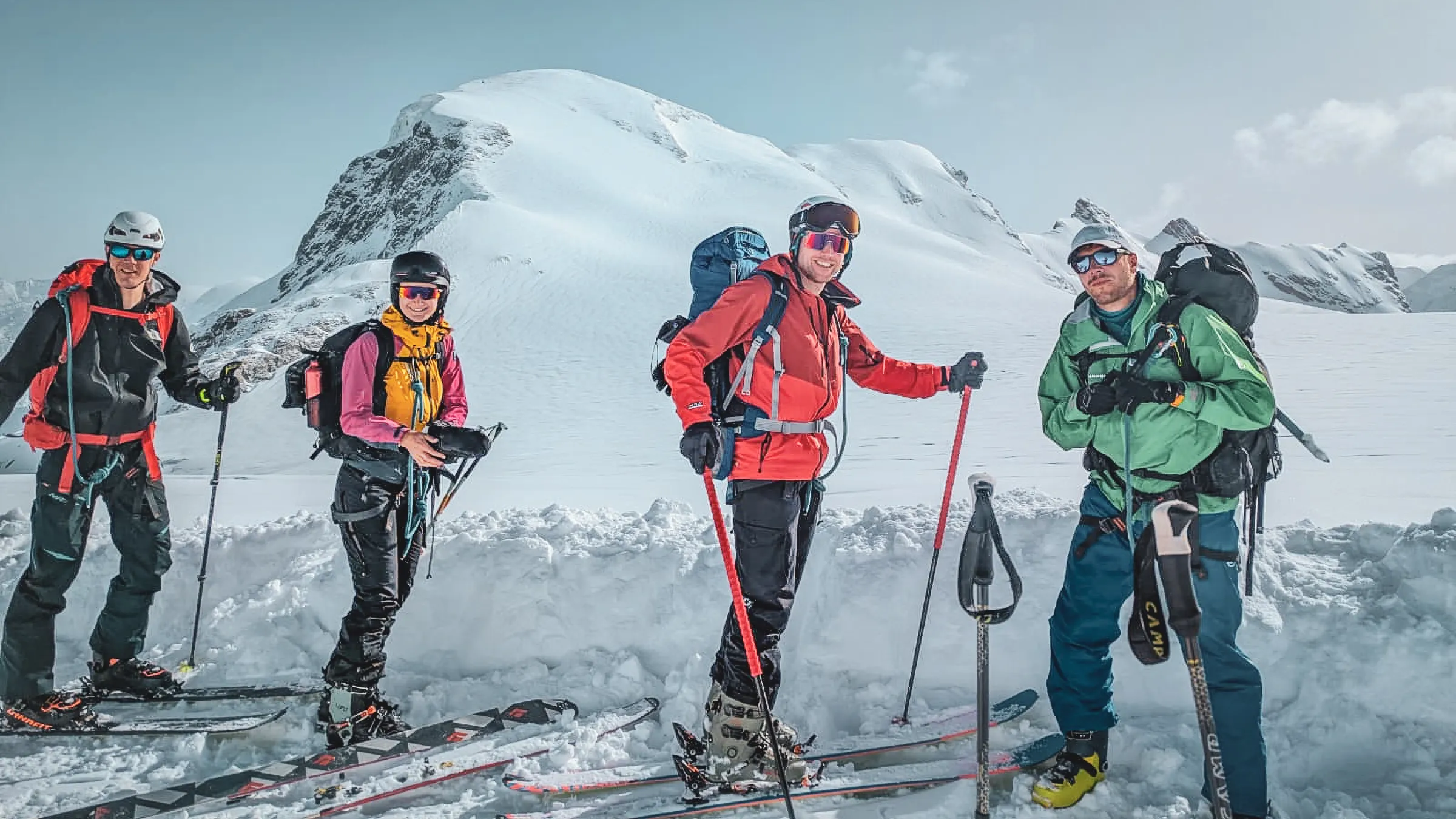 Quatre skieurs en pleine expédition sur les glaciers majestueux du Mont Rose, sous un ciel clair.