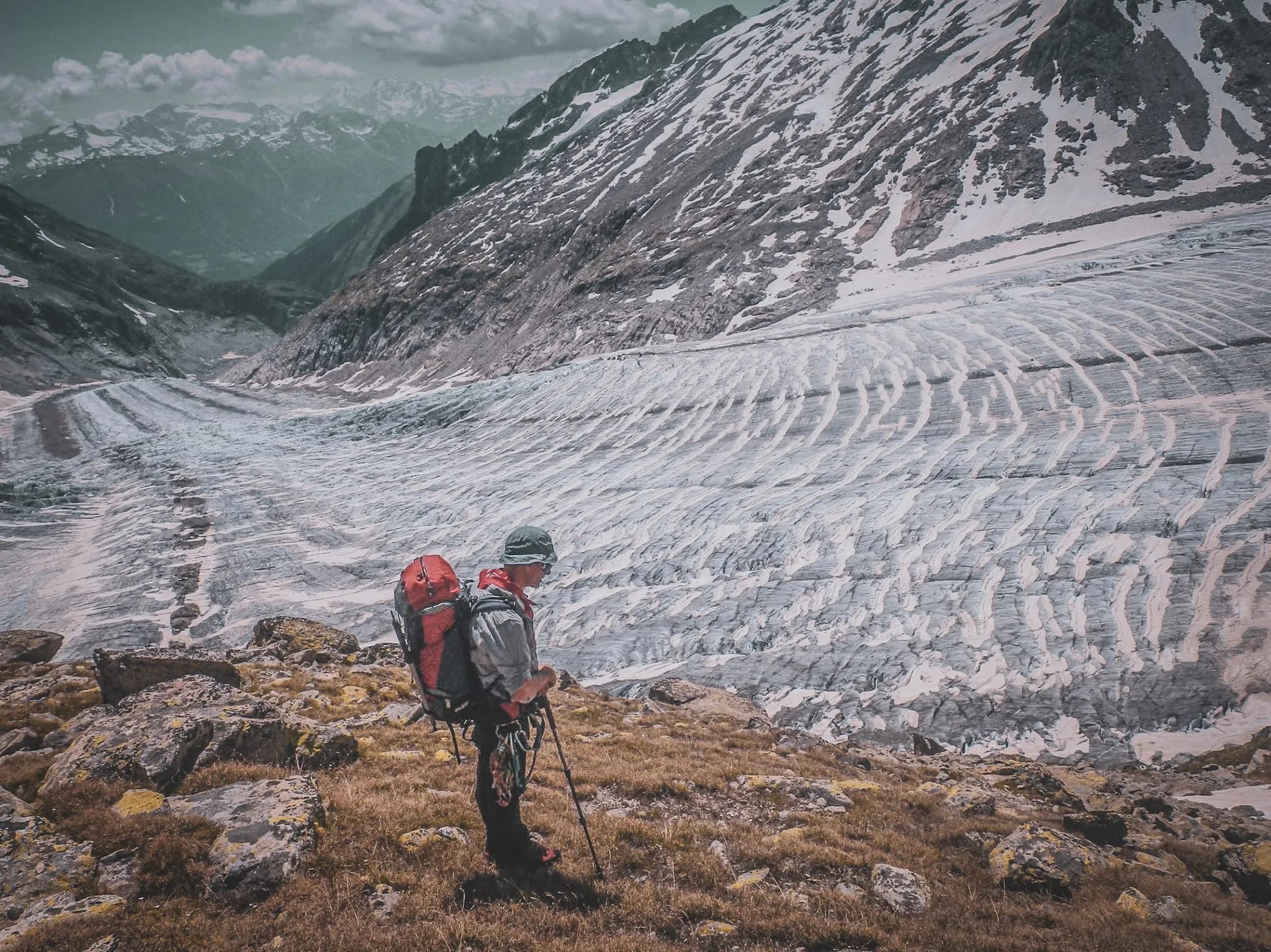 A hiker in front of the majestic Aletsch glacier, a breathtaking Alpine panorama.