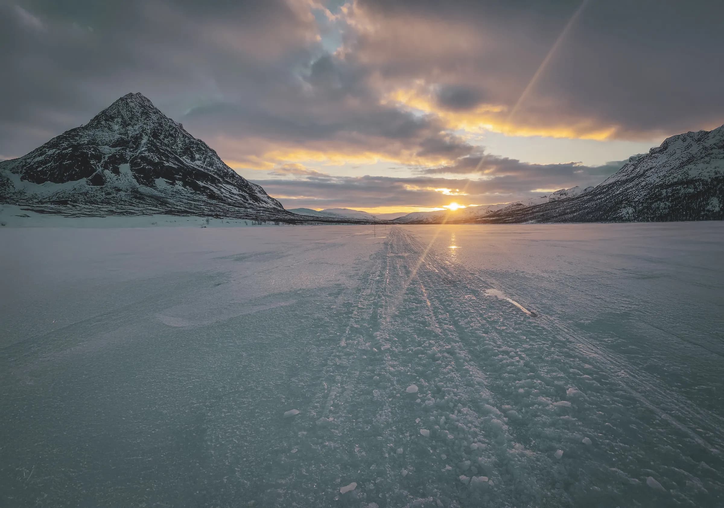 Breathtaking scenery of snow-capped mountains under a colourful sky at sunset on the Kungsleden.