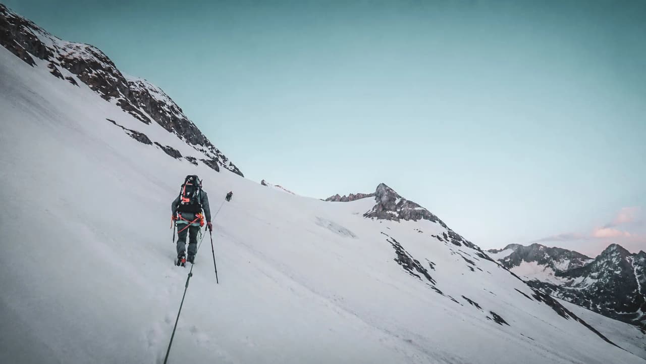 Wandelaars op een besneeuwde helling met de Mont Blanc als majestueuze achtergrond.