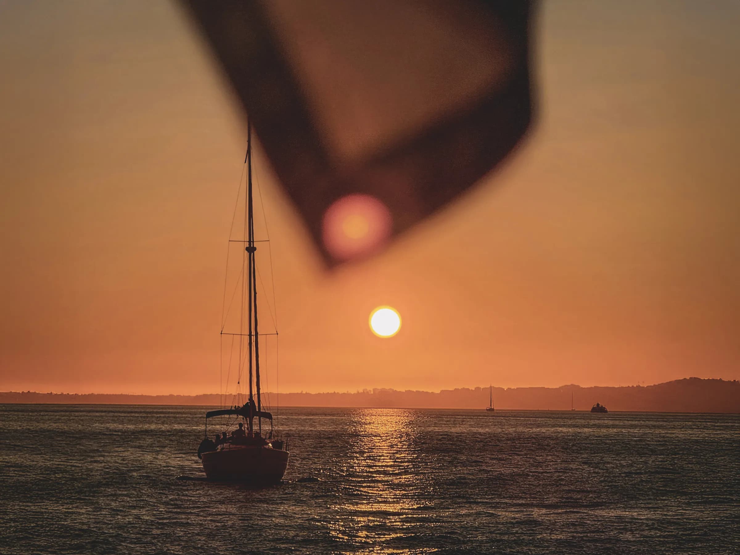 Voilier silhouetté au coucher du soleil, reflet doré sur les eaux tranquilles de Corse.