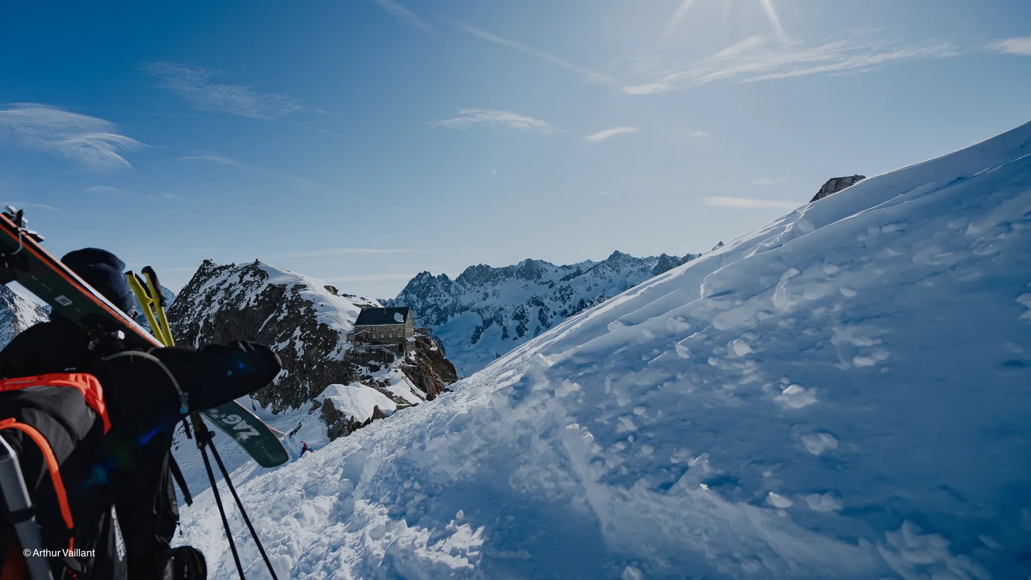 A skier gazing out over a snow-covered alpine landscape, with majestic peaks in the background.