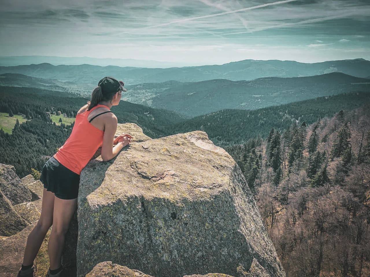 A hiker contemplating a majestic panorama of the Vosges from a sun-drenched rock.