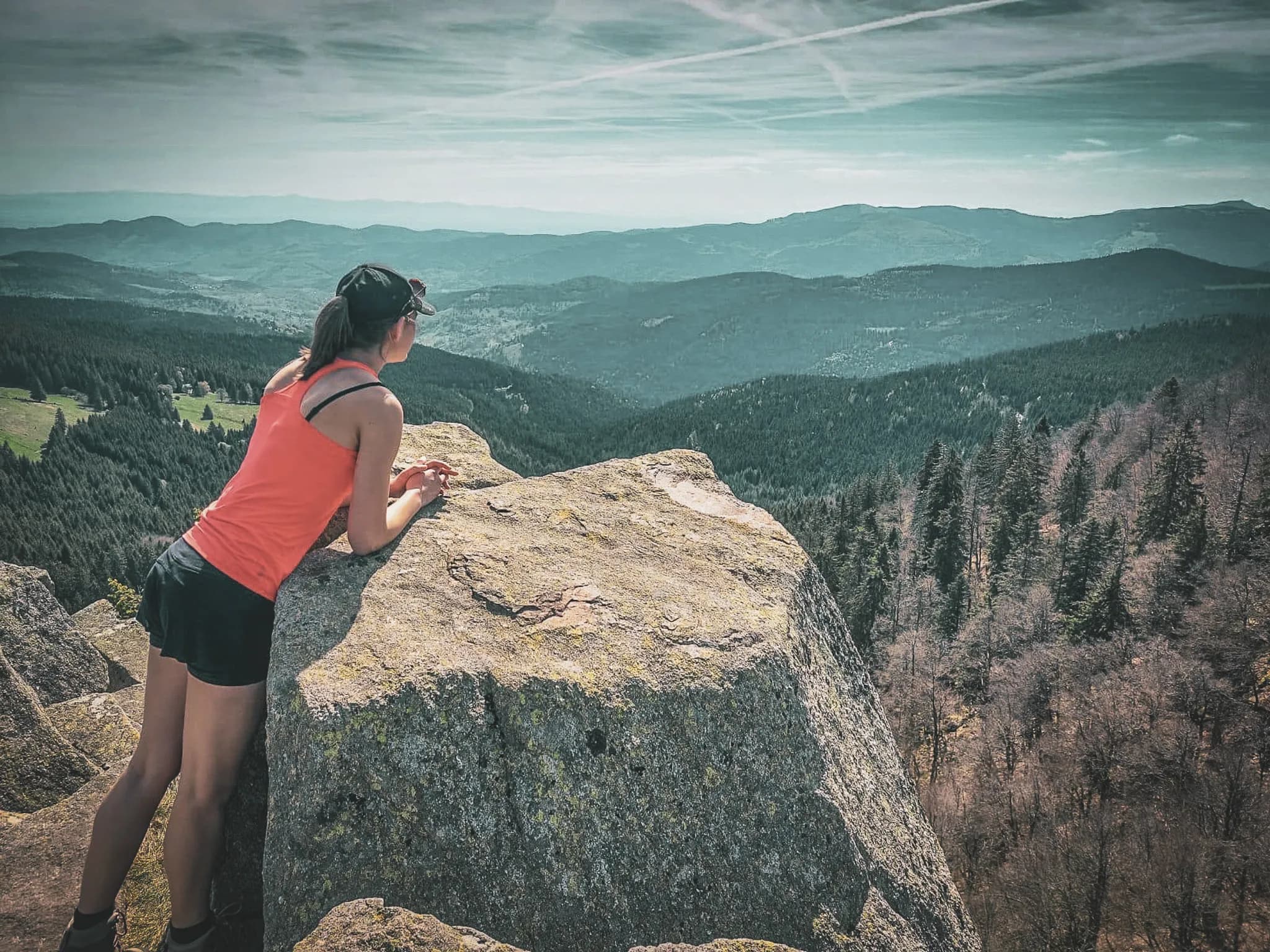 A hiker contemplating a majestic panorama of the Vosges from a sun-drenched rock.