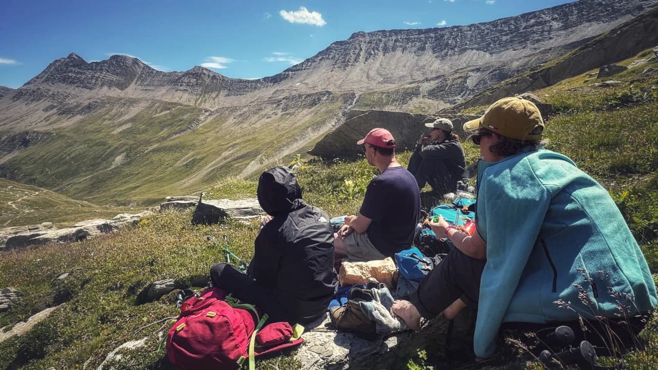 A group of hikers rest on the rocks, admiring the enchanting mountain scenery.