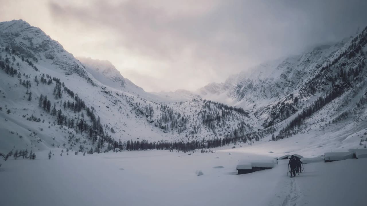 Stunning Alpine scenery in the snow, with majestic mountains and hikers.