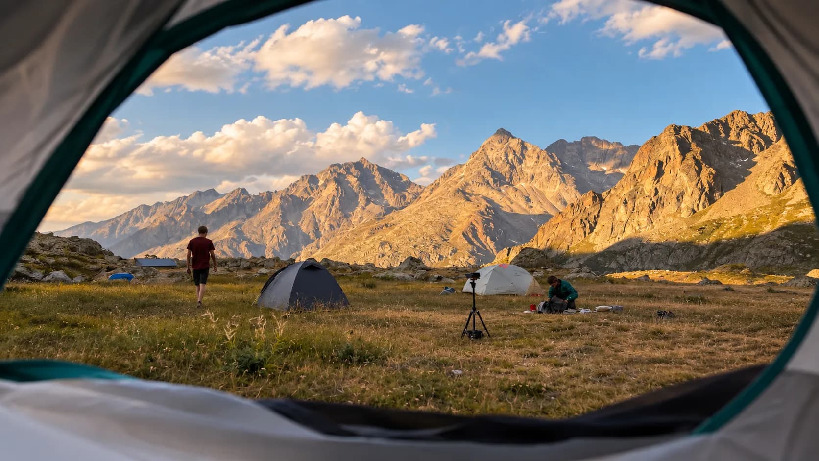 Vue depuis une tente au coucher du soleil, montagnes majestueuses et bivouac paisible.