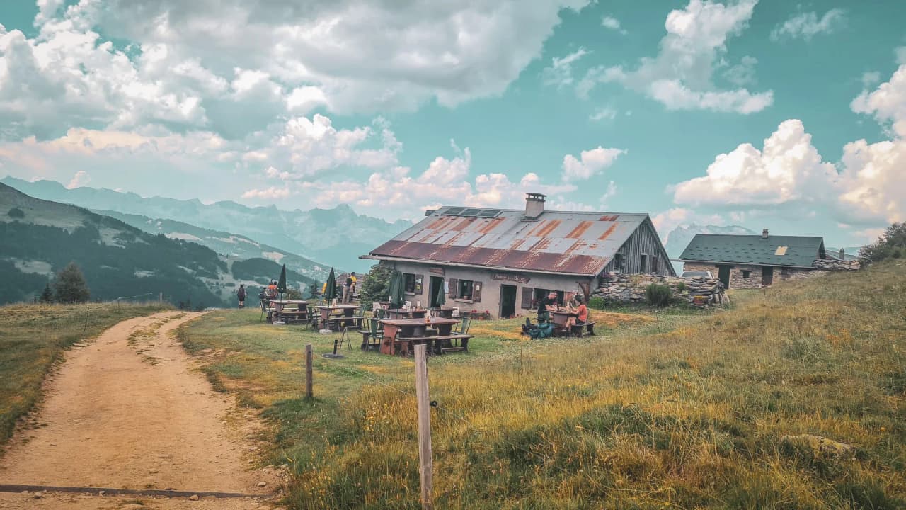 A picturesque mountain hut surrounded by lush green landscapes and majestic peaks.