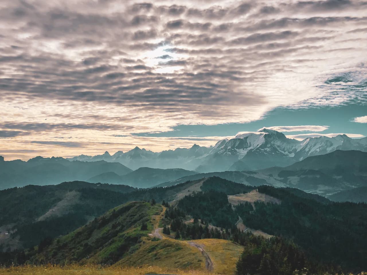 Panoramic view of the green ridges of the Val d'Arly, with the majestic Mont-Blanc in the background.
