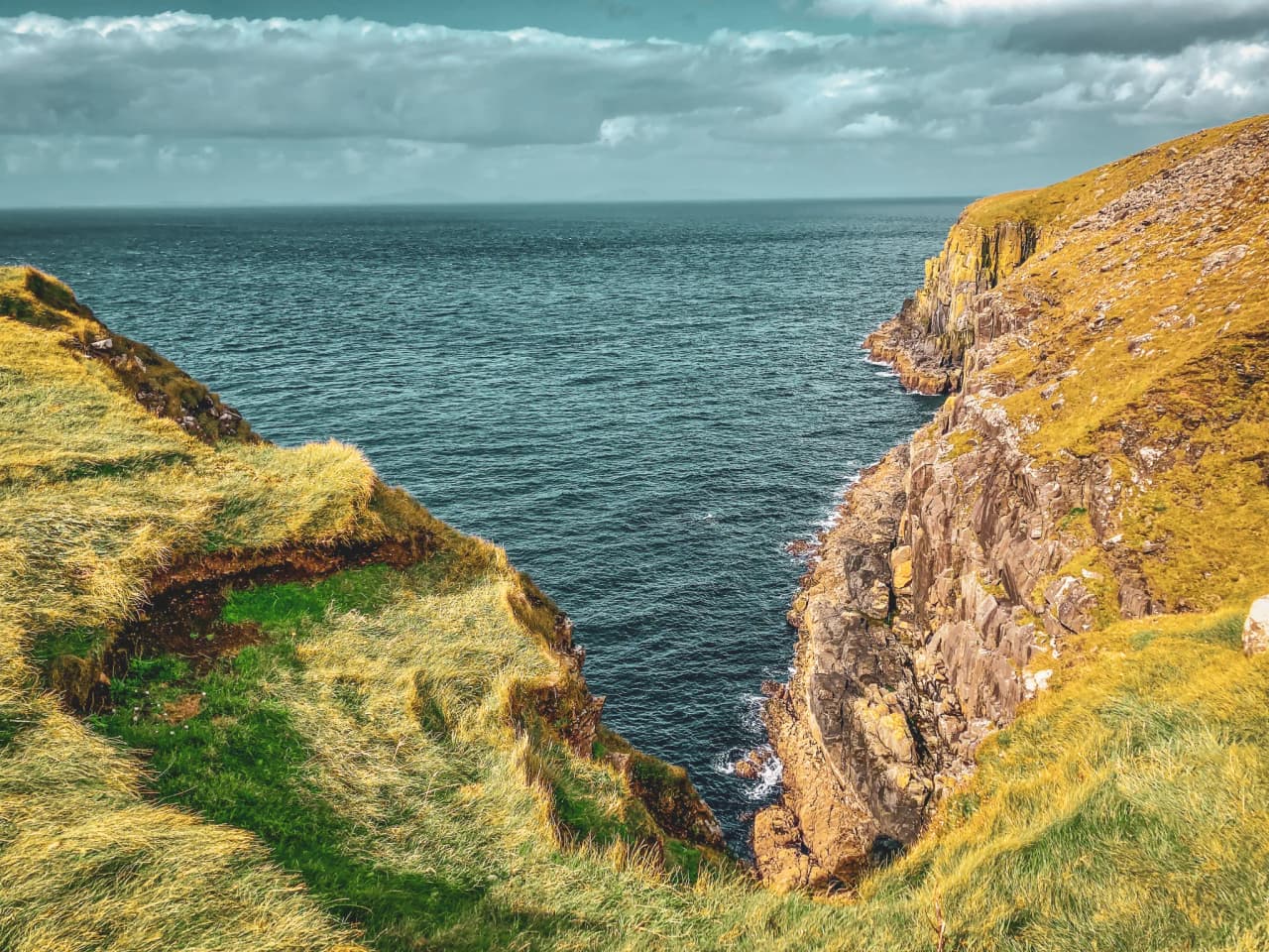 Falaises impressionnantes sur l'île de Skye, surplombant une mer bleu profond, paysages à couper le souffle.