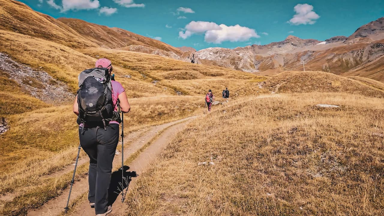 Een groep wandelaars in de gouden landschappen van het Vanoise National Park, blauwe luchten en vrijheid.