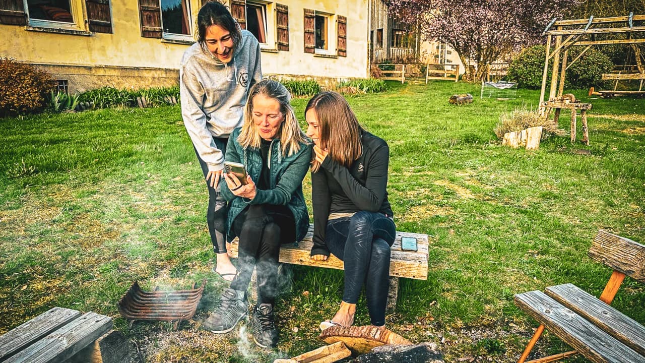 Three friends enjoy a cosy moment by a fire, surrounded by nature in the Vosges.
