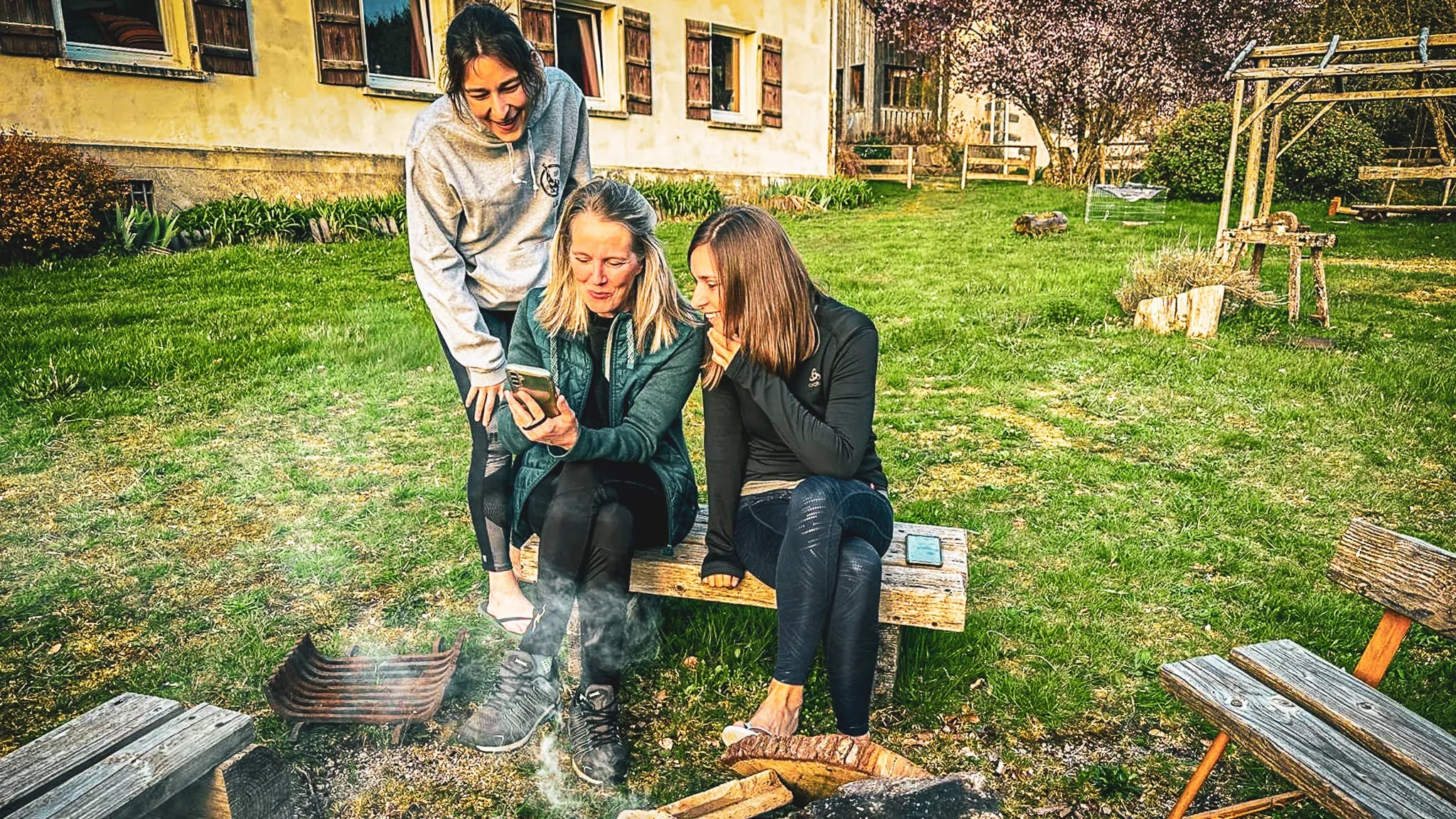 Trois amies profitent d'un moment convivial près d'un feu, entourées par la nature des Vosges.