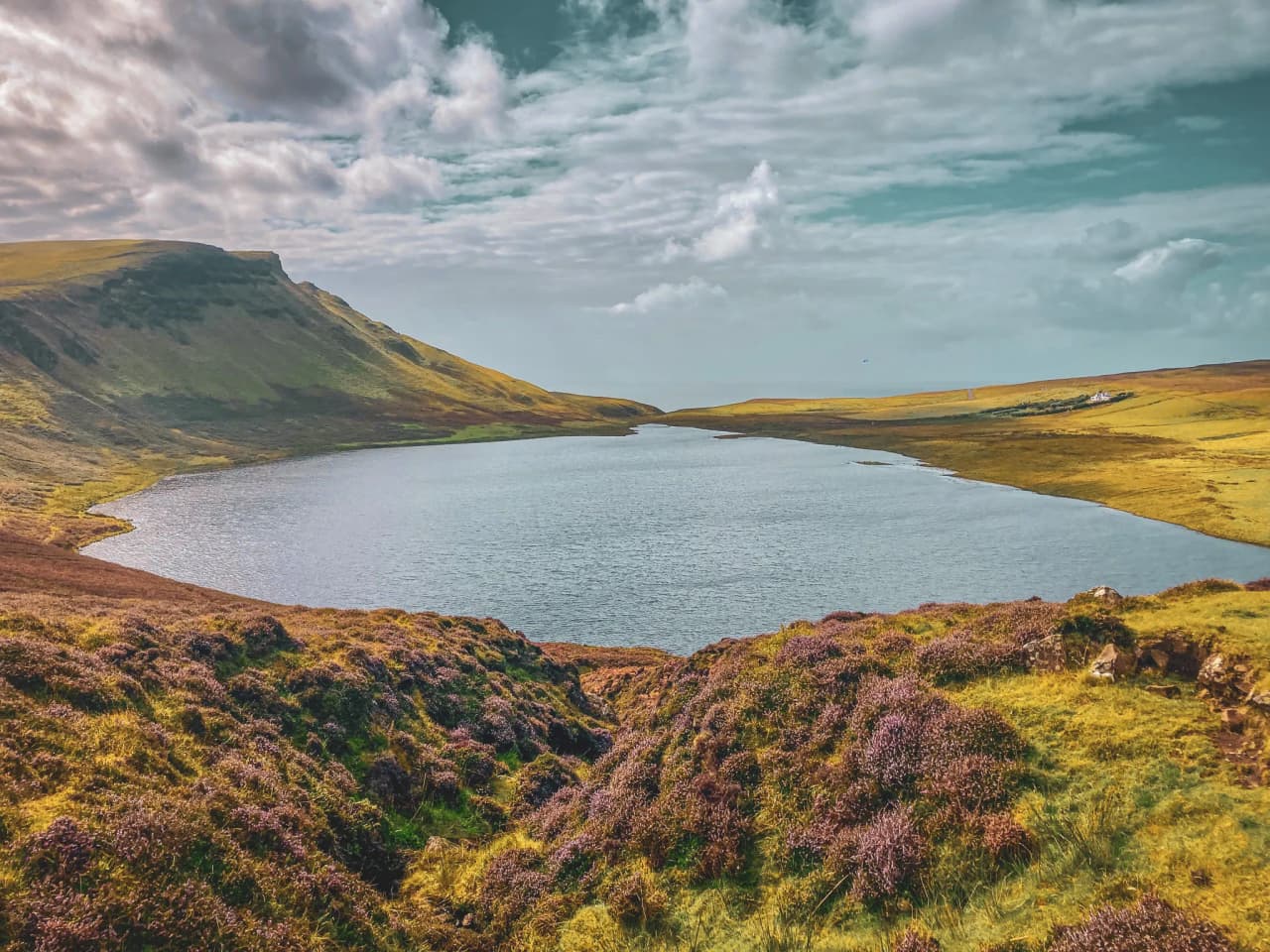 Lac paisible entouré de collines verdoyantes et de bruyères violettes sur l'île de Skye.