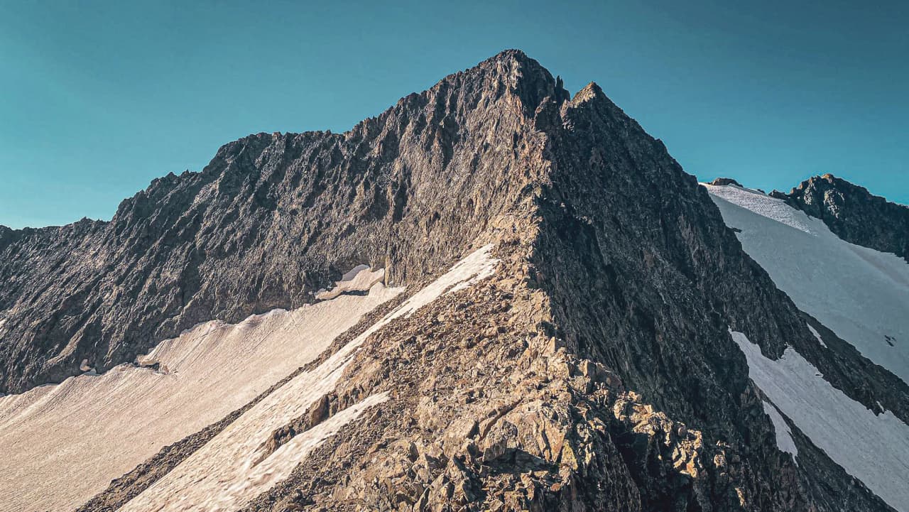 Montagne majestueuse des Écrins, sommets rocheux et glaciers sous un ciel azuré. Aventure alpine assurée!