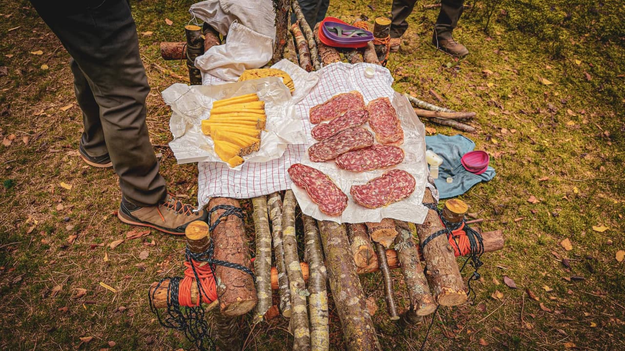 Un plateau de charcuterie et fromage en pleine nature, entouré de forêts verdoyantes.