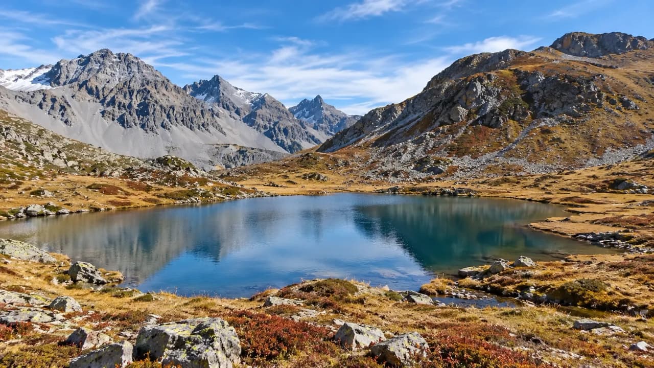 Lac cristallin entouré de montagnes majestueuses et de paysages alpins colorés.