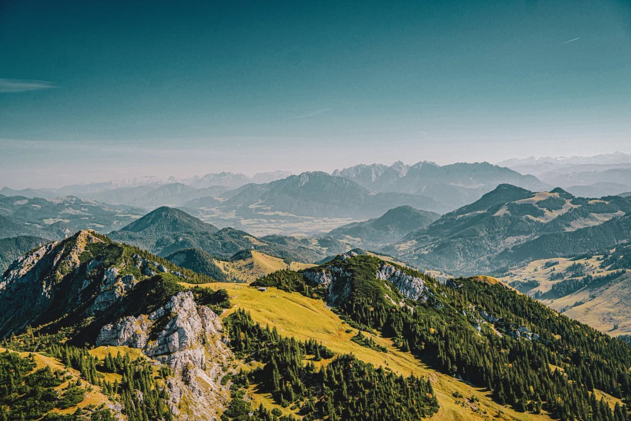 An enchanting panorama of the Jura mountains, with lush green valleys under azure skies.