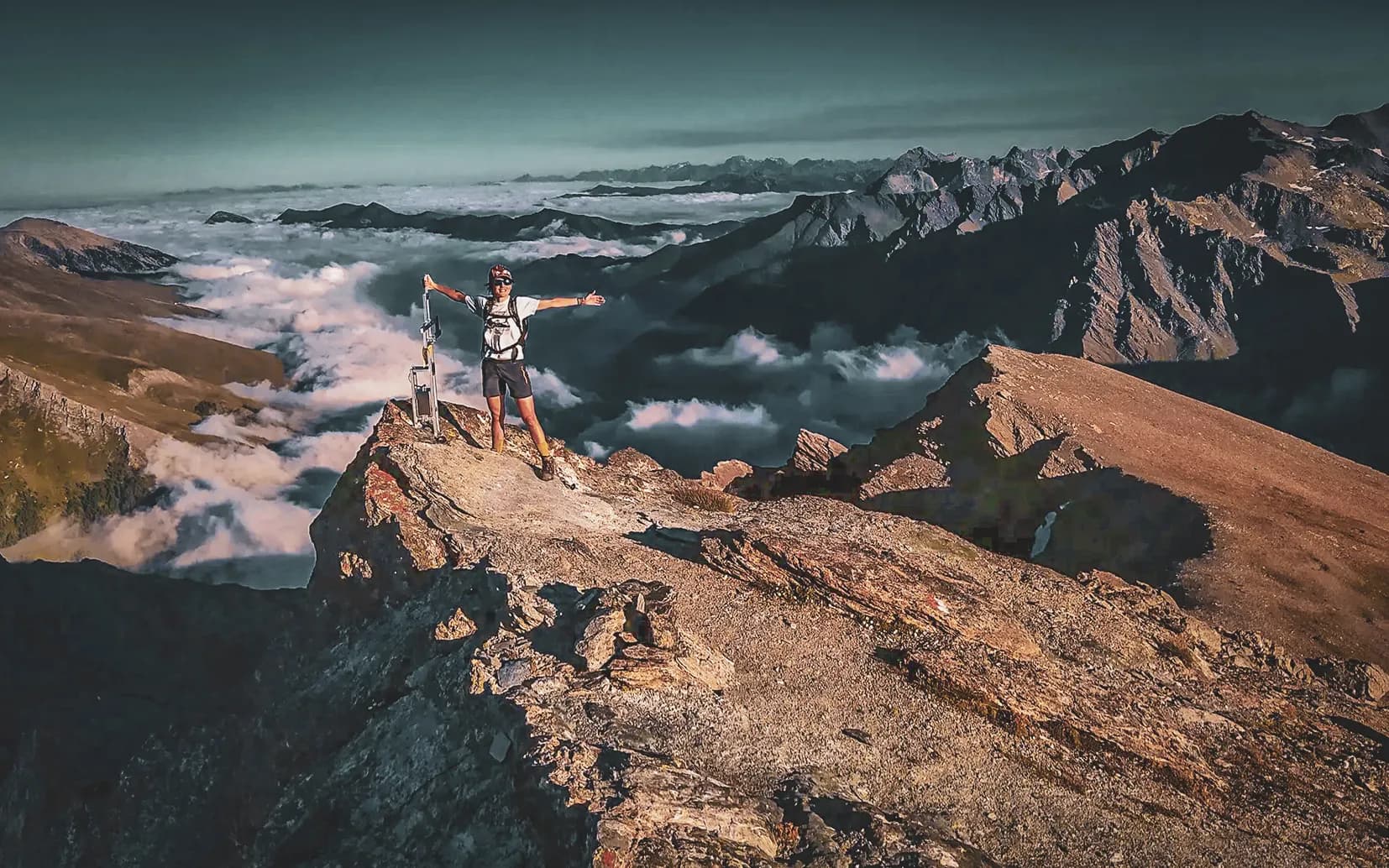 A blossoming hiker at the top of a mountain, stretching out above the clouds.