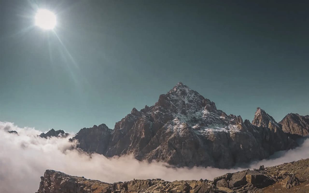 Mont Viso, majestueus onder een blauwe hemel, torenhoog boven de wolken, een uitnodiging tot alpien avontuur.